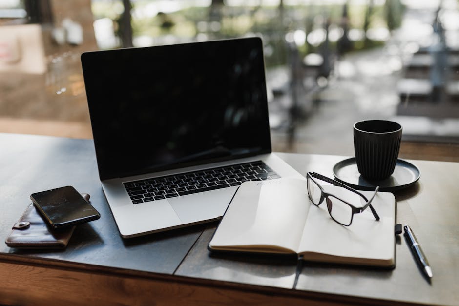A modern workspace with a laptop, coffee, and notepad on a desk.