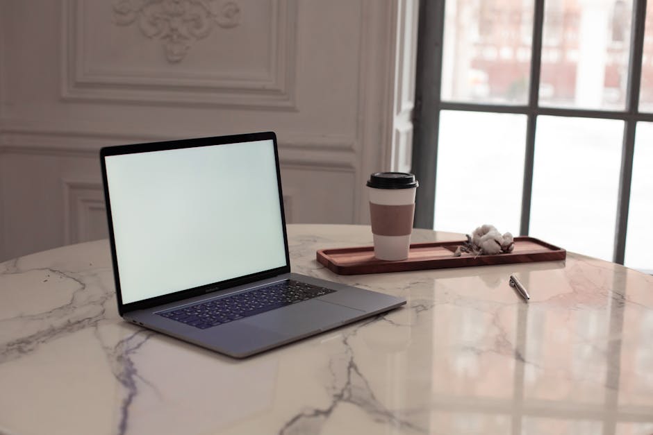 A modern office desk with a laptop and coffee cup in soft light.