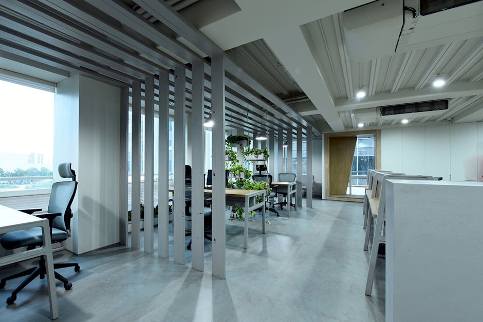A contemporary office setting with desks, plants, and soft lighting.