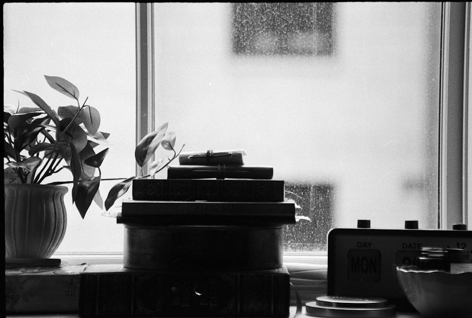 A stack of books, microphone, and clock on a wooden table