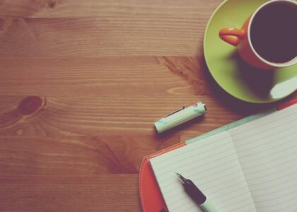 A modern workspace with a laptop, notepad, and coffee cup on a desk.