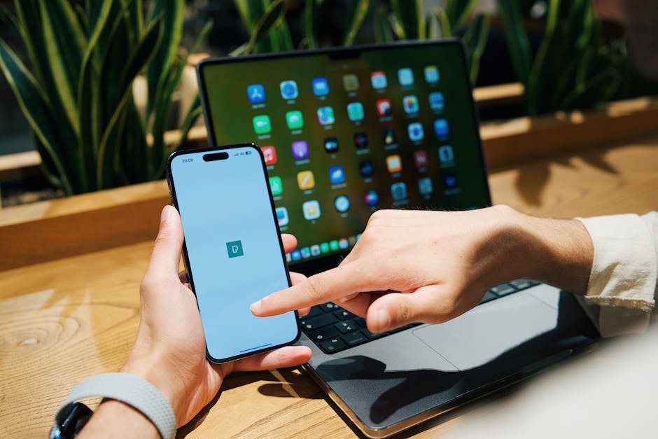 Modern laptop and smartphone on a wooden desk with soft lighting.