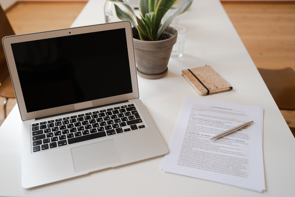 A modern desk setup with a laptop and financial documents under soft lighting.