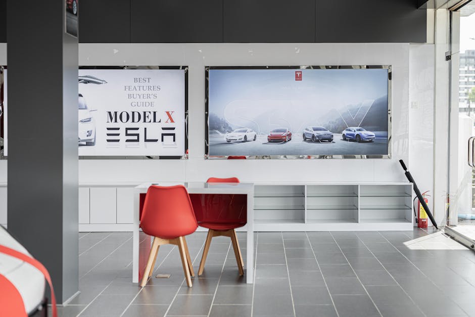 Interior of a modern automotive dealership with empty desks and screens.