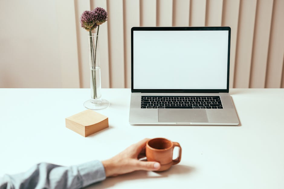 A modern workspace with a laptop, sticky notes, and a coffee cup