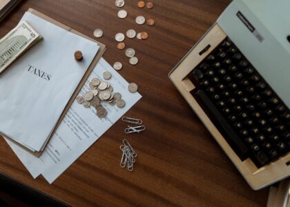 A rustic desk with a calculator, coins, and a plant under natural light.
