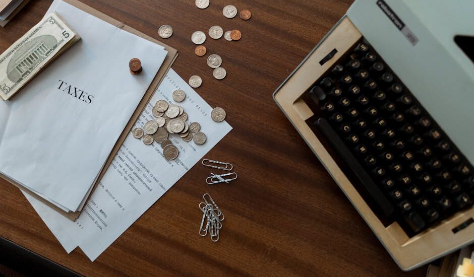 A rustic desk with a calculator, coins, and a plant under natural light.