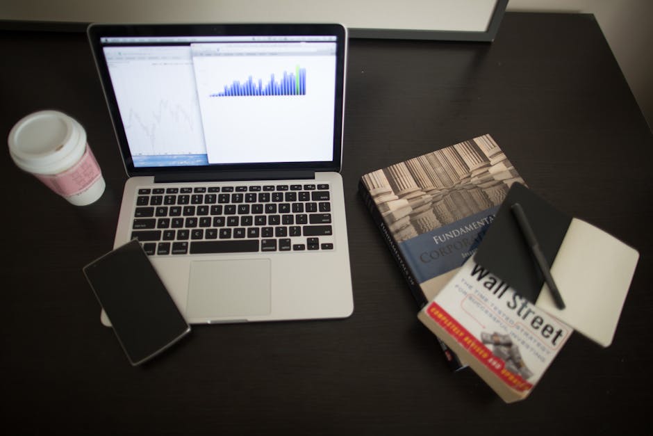 A modern workspace with a laptop and financial charts on a desk.