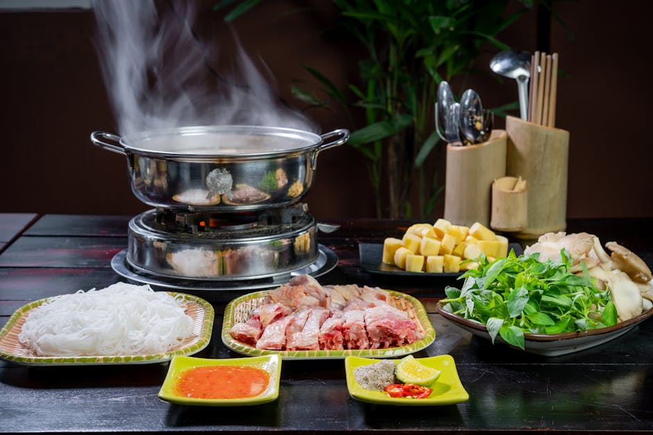 A colorful hotpot setup with fresh ingredients on a wooden table.