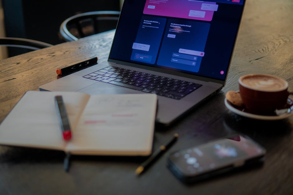 A cozy workspace with a laptop, coffee cup, and notepads.