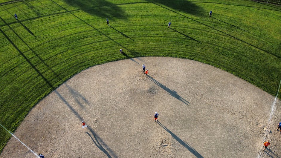 A sunny baseball field with a clear blue sky and well-maintained grass.