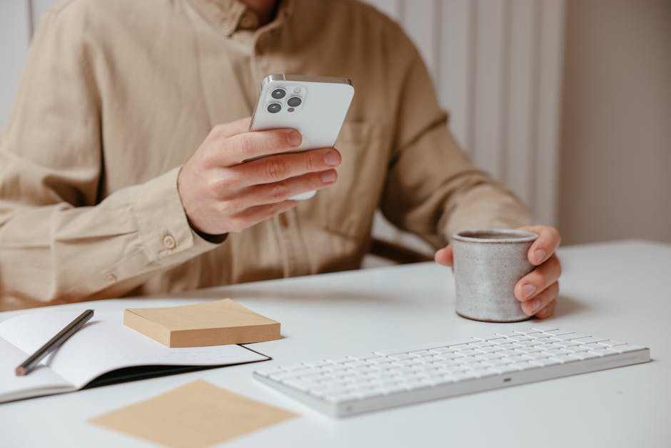 A smartphone on a desk with sticky notes and a coffee cup.