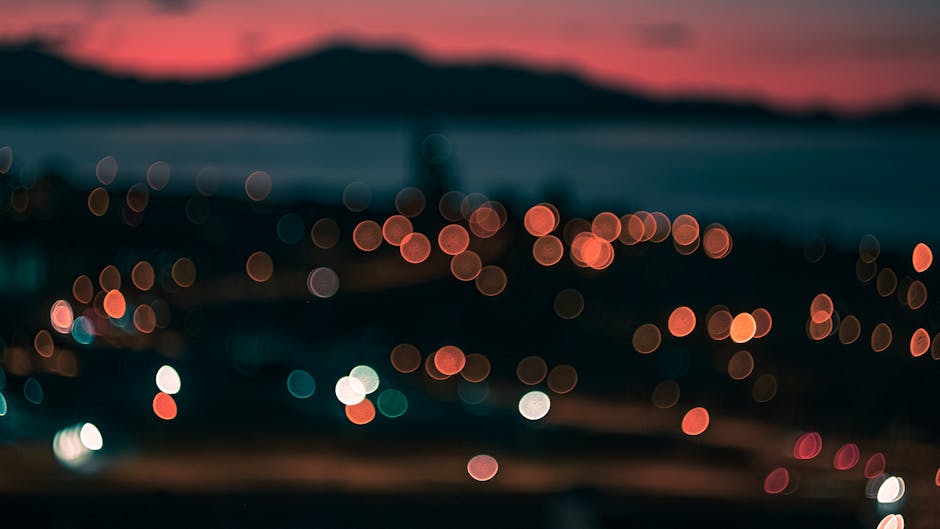 Blurred city skyline at dusk with glowing lights and a tranquil atmosphere.