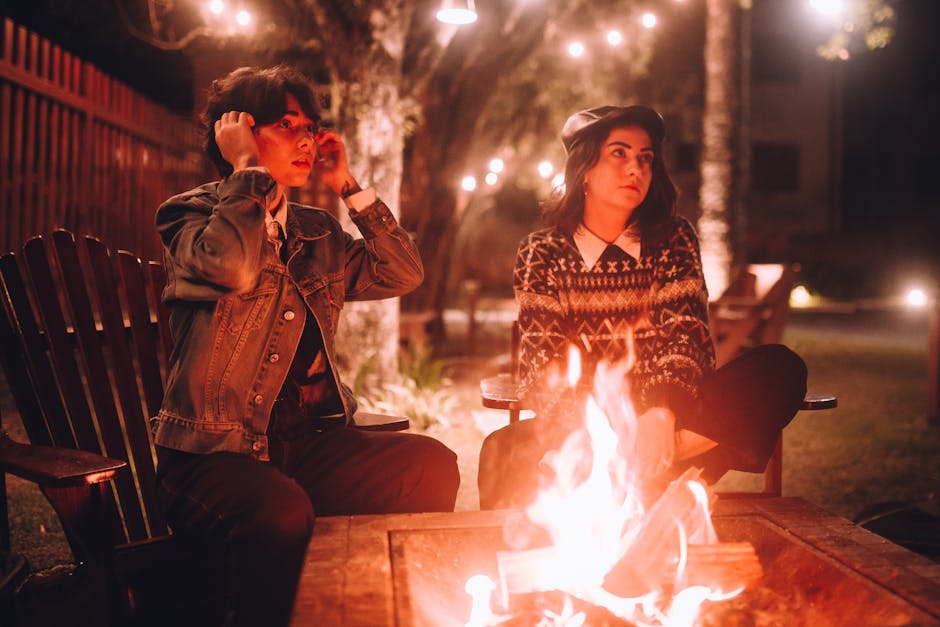 A cozy gathering of friends around a fire pit in a green setting.
