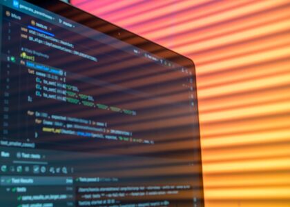 A colorful workspace with coding books and a laptop under natural light.